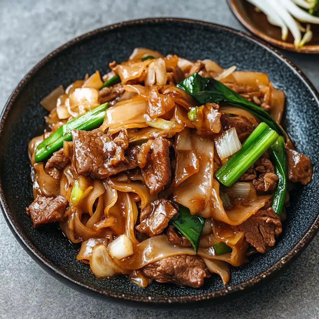 Close-up of juicy beef and glossy noodles in chow fun dish